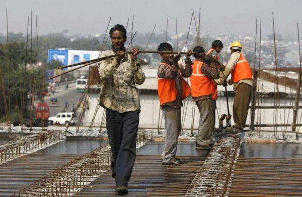 Indian workers carry metal rods on an overpass bridge in Jammu, India, Monday, 29 February 2016