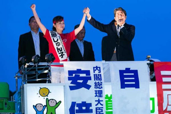 LDP candidate Junko Mihara, and LDP leader and Prime Minister of Japan Shinzo Abe, raise joined hands during a campaign event for July’s House of Councillors elections outside Sakuragicho Station on 27 June 2016. (Photo: AAP).