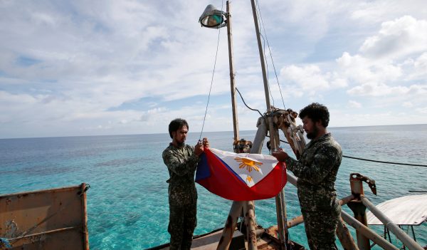 Philippine Marines fold a Philippine national flag during a flag retreat at the BRP Sierra Madre, a marooned transport ship in the South China Sea. (Photo: Reuters).