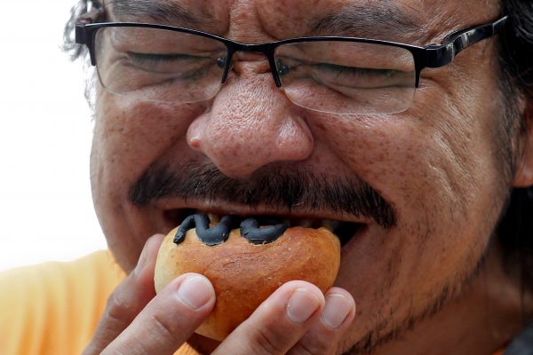 A man eats a bread with ‘no’ written on it during a campaign against junta-backed draft constitution, ahead of the referendum, Thailand, 24 July 2016. (Photo: Reuters).