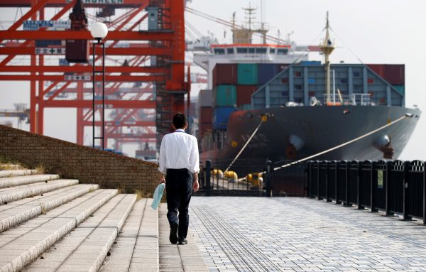A man walks near a container ship at a port in Tokyo, Japan, 20 October 2015. (Photo: Reuters).