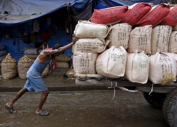 A labourer pushes a handcart loaded with sacks containing tea packets towards a supply truck at a wholesale market in Kolkata, India, 26 June 2015. (Photo: Reuters).