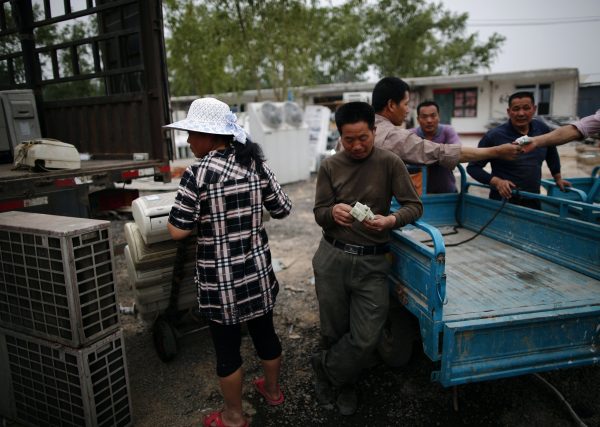 A man counts his money after selling recycled air-conditioning units to a vendor in the yard of a tenement house at Dongxiaokou village in Beijing. (Photo: Reuters).