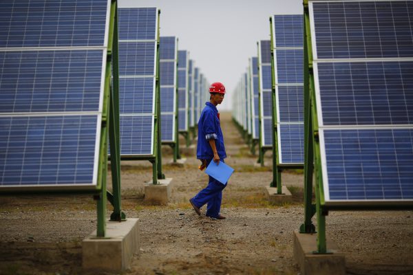 A worker inspects solar panels at a solar farm in Dunhuang, China, 16 September 2013. (Photo: Reuters)