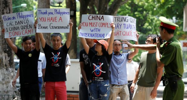 A policeman tries to stop anti-China protesters holding placards during a demonstration in front of the Philippines embassy in Hanoi, Vietnam, July 17, 2016. (Photo: Reuters).