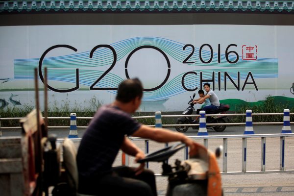 People cycle past a billboard for the upcoming G20 summit in Hangzhou, China, 29 July 2016. (Photo: Reuters).