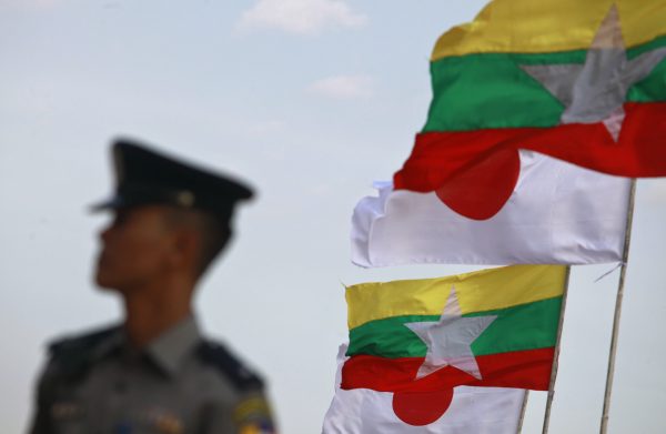 A police officer stands on guard near national flags of Myanmar and Japan during the commencement ceremony of the Thilawa Special Economic Zone (SEZ) project in the Japanese Special Economic Zone at Thilawa outside Yangon. (Photo: Reuters).