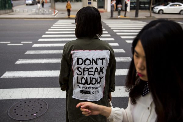 A woman wearing a jacket reading ‘Don't Speak Loudly’ waits at a traffic light in the fashion district of Apgujeong in Seoul, 7 May 2015. (Photo Reuters).
