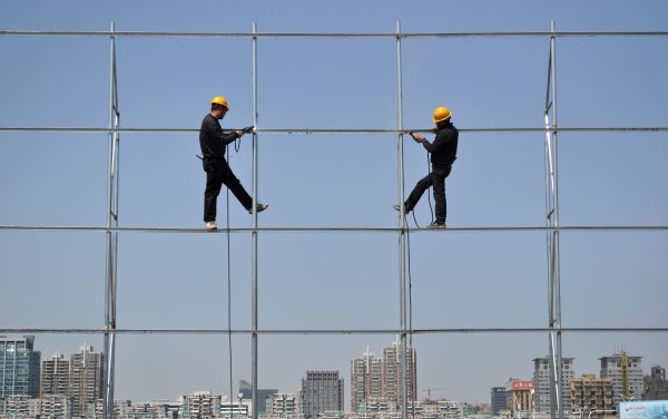 Workers stand on a steel frame that they are welding for an advertising board in Jiaxing, Zhejiang province, China, 24 March 2012. (Photo: Reuters)