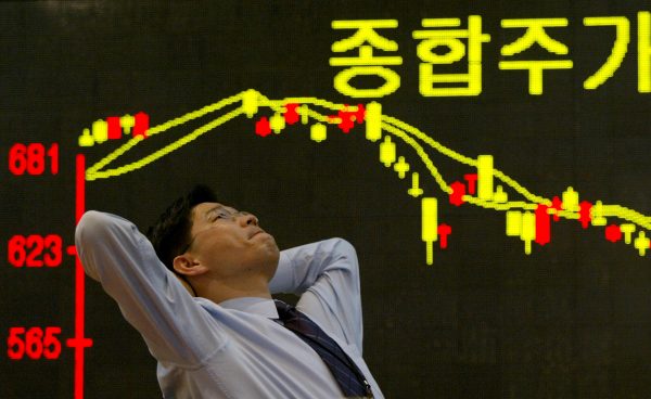 A South Korean employee of a securities firm reacts in front of a graph showing stock price in Seoul, South Korea, 11 March 2003. (Photo: Reuters)