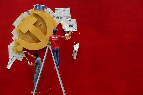 Workers peel papers off a wall as they re-paint the Chinese Communist Party flag on it at the Nanhu revolution memorial museum in Jiaxing, Zhejiang province, China, 21 May 2014. (Photo: Reuters)