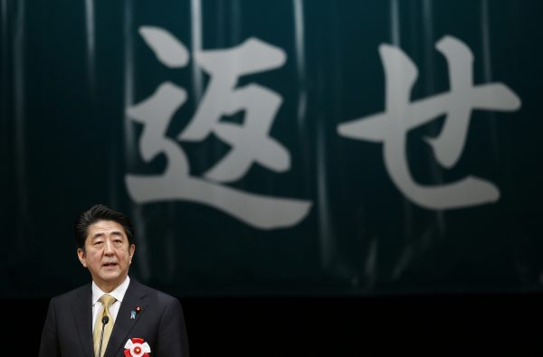 Japan's Prime Minister Shinzo Abe speaks in front of a banner reading ‘return’ during a Northern Territories Day rally to call on Russia to return a group of islands, known as the Northern Territories in Japan and the Southern Kuriles in Russia, in Tokyo, Japan, 7 February 2015. (Photo: Reuters/Yuya Shino).