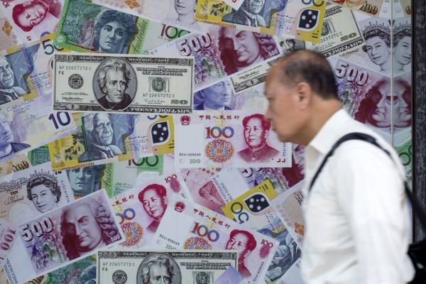 A man walks past an advertisement promoting renminbi, US dollar and euro exchange services at a foreign exchange store in Hong Kong, China, 13 August 2015. (Photo: Reuters/Tyrone Siu).