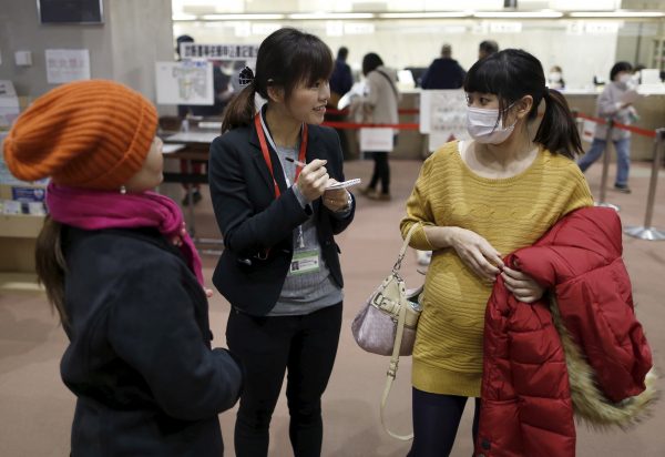 Interpreter Dang Nguyen Thuc Vien, centre, the daughter of refugees from South Vietnam, helps a Vietnamese resident at a hospital in Kanagawa prefecture, south of Tokyo. If controls were relaxed, immigration could initially focus on the needs of specific industries (Photo: Yuya Shino/Reuters).