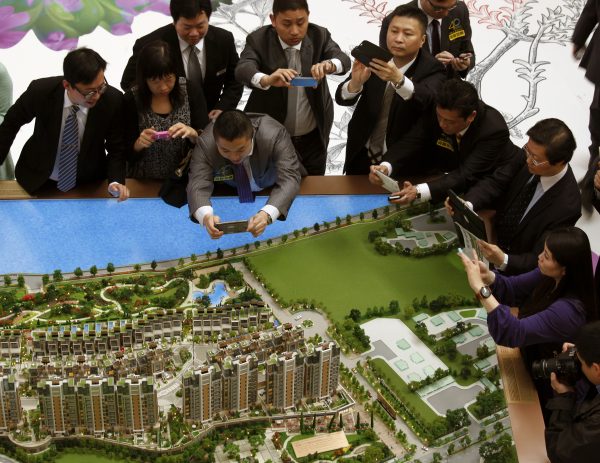 Property sales agents take photos during the roadshow of a residential property development by major developer Sun Hung Kai Properties (Photo: Reuters).