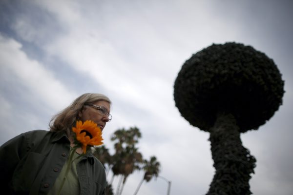 A woman holds a sunflower at a peace vigil in front of ‘Chain Reaction,’ a mushroom cloud sculpture as a symbol of a world free of nuclear weapons, in Santa Monica, California. (Photo: Reuters/Lucy Nicholson).
