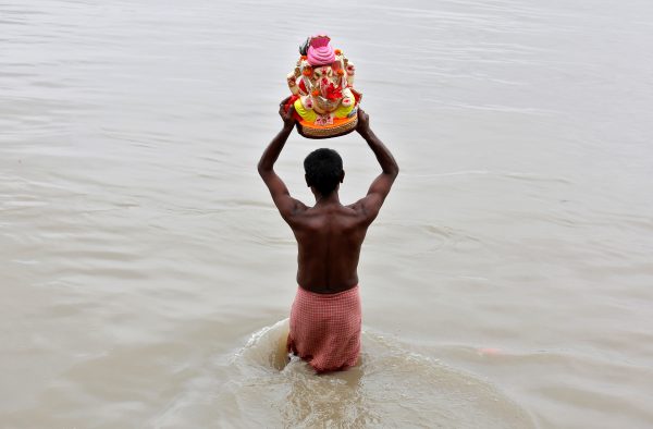 A devotee carries an idol of the Hindu god Ganesh, the deity of prosperity, for immersion in the waters of the river Ganges. (Photo: Reuters/Rupak De Chowdhuri).