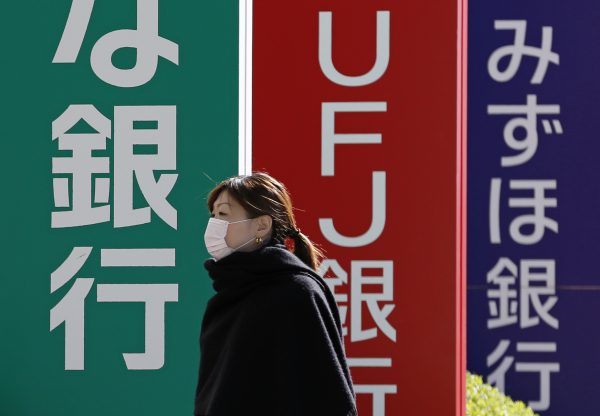 A pedestrian walks past signboards of Resona Bank (L), Bank of Tokyo-Mitsubishi UFJ (C) and Mizuho Bank in Tokyo, Japan, 14 November 2014. (Photo: Reuters/Yuya Shino).