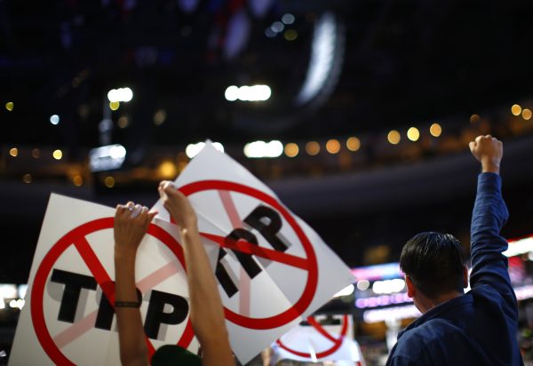 Delegates protesting against the Trans Pacific Partnership (TPP) trade agreement hold up signs during the first session at the Democratic National Convention in Philadelphia, Pennsylvania, US, 25 July 2016. (Photo: Reuters/Carlos Barria).