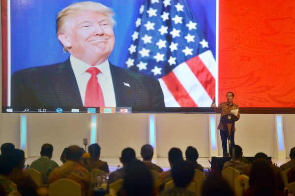 Indonesian President Joko Widodo speaks to local company executives as a picture of US President-elect Donald Trump is shown on a screen behind him (Photo: Antara Foto/Reuters).