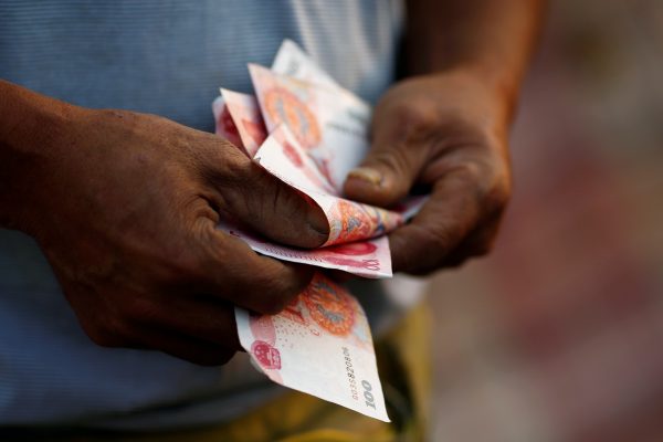 A worker counts money at a recycling yard as he poses for a picture in Beijing, China, 21 September 2016. (Photo: Reuters/Thomas Peter).