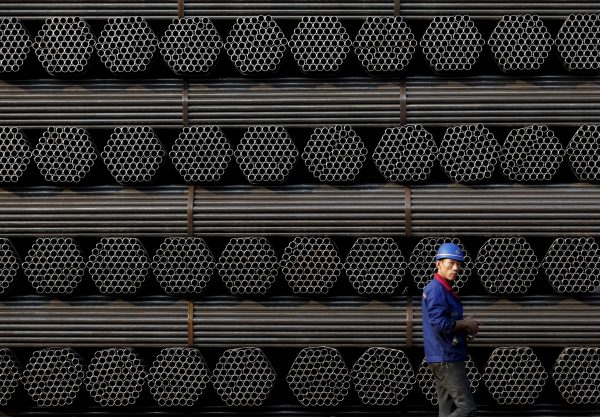 A worker walks past a pile of steel pipe products in China's Hebei Province (Photo: Kim Kyung-Hoon/Reuters).