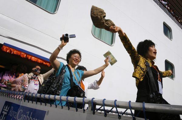 Tourists from China wave as they arrive on a cruise ship in the northern Taiwan port of Keelung March 16, 2009. A total of 1,600 employees from Amway China arrived on Monday, the first large-scale tour group from the mainland via a foreign-owned cruise ship since the opening of direct transport links from the mainland last year. (Photo: Reuters/Nicky Loh).