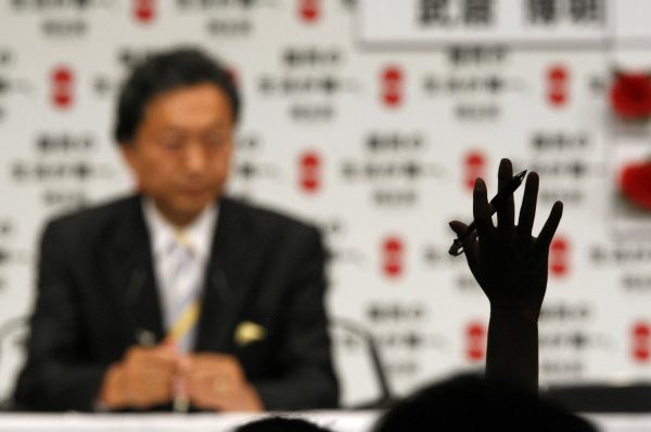 A hand of a reporter is raised as Japan's main opposition Democratic Party leader Yukio Hatoyama speaks to journalists during a news conference at the Democratic Party of Japan election headquaters in Tokyo 31 August 2009. Japanese voters swept the opposition to a historic victory in Sunday's election, exit polls showed, crushing the long-ruling conservative party and handing the novice Democrats the job of reviving a struggling economy. (Photo: Reuters/Issei Kato).