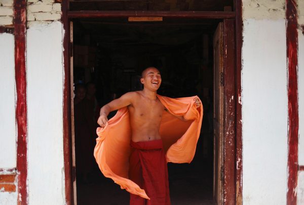 A Buddhist monk smiles as he adjusts his robe while speaking with his friend at a monastery in Yangon 13 March 2012 (Photo: Reuters).