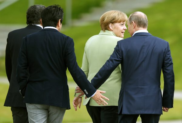 Japan's Prime Minister Shinzo Abe (2nd L) touches hands with Russia's President Vladimir Putin as they walk with Germany's Chancellor Angela Merkel, after a G8 summit group photograph was taken at the Lough Erne golf resort in Enniskillen, Northern Ireland, United Kingdom, 18 June 2013. (Photo: Reuters/Andrew Winning).