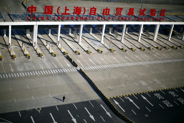 A man walks in front of the entrance of the Shanghai Pilot Free Trade Zone at the Pudong international airport in Shanghai (Photo: Reuters/Carlos Barria).