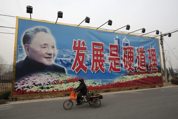 A woman rides a tricycle past a giant poster of late Chinese leader Deng Xiaoping in Beijing. The poster reads, ‘Development is the absolute principle’. China has come a long way since Deng initiated economic reforms in 1978, but much remains to be done to create a more sustainable China model. (Photo: Reuters/Reinhard Krause).