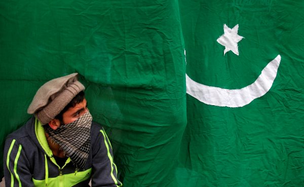 A masked protester sits next to a flag of Pakistan during an anti-Indian protest in Srinagar, 25 November 2016. (Reuters/Danish Ismail).