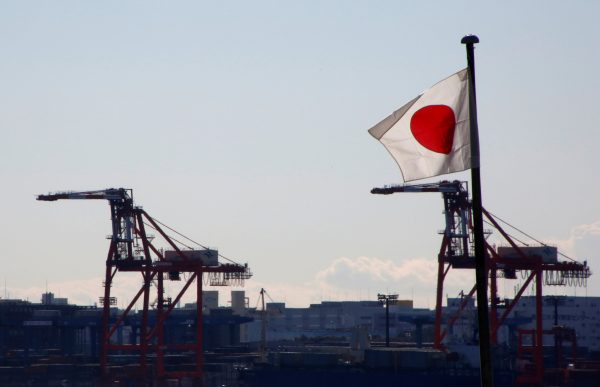 Japan's national flag is seen in front of containers and cranes at an industrial port in Tokyo, Japan, 25 January 2017 (Photo: Reuters/Kim Kyung-Hoon).