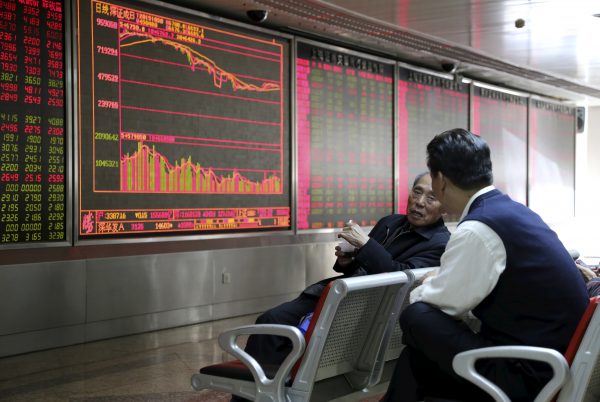 Investors chat in front of an electronic board showing stock information at a brokerage house in Beijing (Photo: Reuters/Li Sanxian).