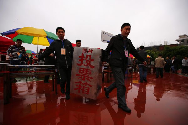 Election officials carry ballot boxes at the end of an election for the next village chief and committee, amid heavy rainfalls in Wukan village, Guangdong province 31 March 2014. People of the southern Chinese village of Wukan carried on with the election amid rainstorm on Monday that some say is threatened by higher government trying to wrestle back control after a landmark rebellion over two years ago. (Photo: Reuters/Petar Kujundzic).