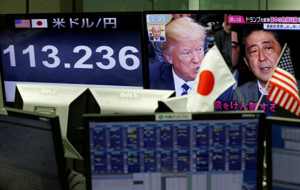 A TV monitor showing US President Donald Trump and Japanese Prime Minister Shinzo Abe is seen next to another monitor showing the Japanese yen's exchange rate against the US dollar at a foreign exchange trading company in Tokyo, Japan, 1 February 2017 (Photo: Reuters/Kim Kyung-Hoon).