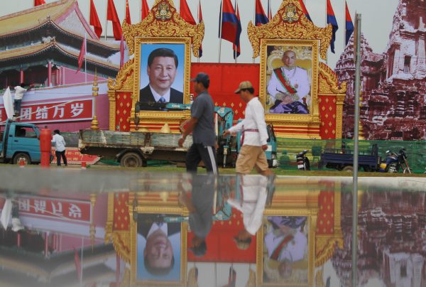 Men walk past portraits of Chinese President Xi Jinping (centre, left) and Cambodian King Norodom Sihamoni ahead of Xi’s visit, in Phnom Penh, Cambodia, 11 October 2016. (Photo: Reuters/Samrang Pring).