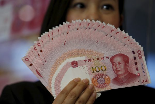 The 2015 edition of the 100 renminbi notes, held up at the Bank of China Tower in Hong Kong, 12 November, 2015 (Photo: Reuters/Bobby Yip).