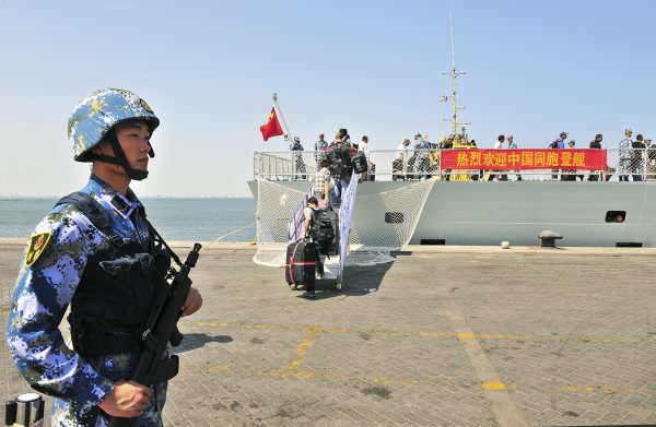 A navy soldier (L) of People's Liberation Army (PLA) stands guard as Chinese citizens board the naval ship ‘Linyi’ at a port in Aden, Yemen, 29 March 2015. (Photo: Reuters/Stringer).