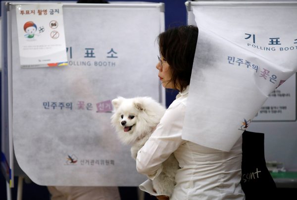 A woman holding her dog casts a preliminary ballot at a polling station in Seoul, South Korea, 4 May 2017. (Photo: Reuters/Kim Hong-Ji).