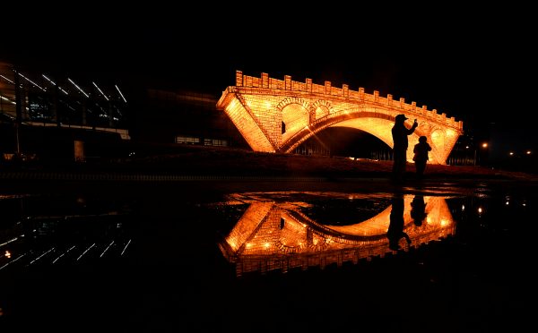 People take pictures in front of a ‘Golden Bridge on Silk Road’ installation, set up ahead of the Belt and Road Forum, outside the National Convention Centre in Beijing, China 11 May 2017 (Photo: Reuters/Stringer).