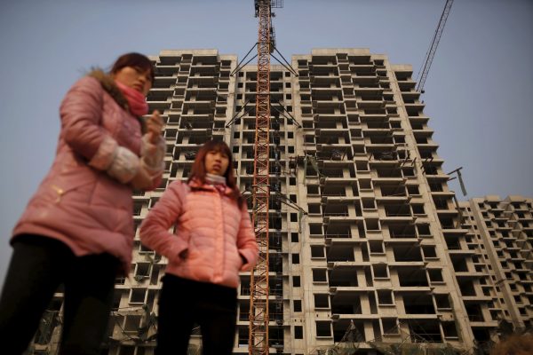 Migrant workers stand in front of a building at the construction site of Changxiang Gardens development complex in Fengrun District, Tangshan City, Hebei province, China, 28 January 2016. (Photo: Reuters/Damir Sagolj).