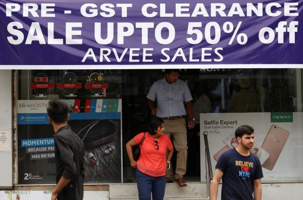 A banner promotes a pre-Goods and Services Tax clearance sale as customers walk out of an electronic shop at a market in New Delhi, India, 22 June 2017 (Photo: Reuters/Adnan Abidi).