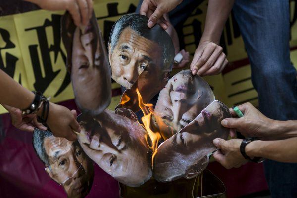 Protesters burn pictures of Singapore's first Prime Minister Lee Kuan Yew and his son and current Prime Minister Lee Hsien Loong outside the Singapore Consulate in Hong Kong, China, 5 July 2015 (Photo: Reuters/Tyrone Siu).