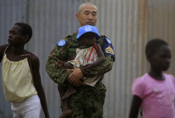 A United Nations peacekeeping engineer from the Japanese Ground Self-Defence Force (GSDF) carries a child inside the Confident Children out of Conflict (CCC) Centre for girls in the Juba capital of South Sudan 1 April 2012. (Photo: Reuters/ Mohamed Nureldin Abdallah).