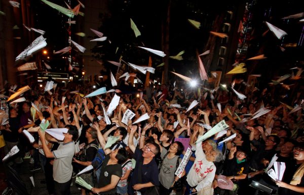 Hundreds of protesters throw paper planes outside the Legislative Council in Hong Kong, 13 July 2011 (Photo: Reuters/Bobby Yip).