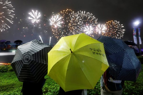 A pro-democracy protester holds a yellow umbrella, the symbol of the Occupy Central movement, as she watches fireworks explode over Victoria Harbour, as part of the celebration for the 20th anniversary of the city's handover from British to Chinese rule, in Hong Kong, China 1 July 2017 (Photo: Reuters/Tyrone Siu).