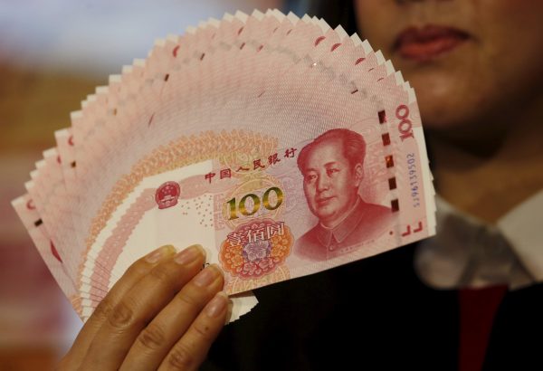 A staffer poses with 2015 edition of the 100 renminbi notes at the Bank of China Tower in Hong Kong, China 12 November 2015. (Photo: Reuters/Bobby Yip).