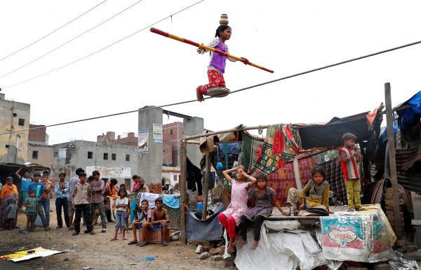A girl performs circus tricks in a slum area of Ghaziabad, on the outskirts of Delhi, India, 28 June 2017 (Photo: Reuters/Cathal McNaughton).